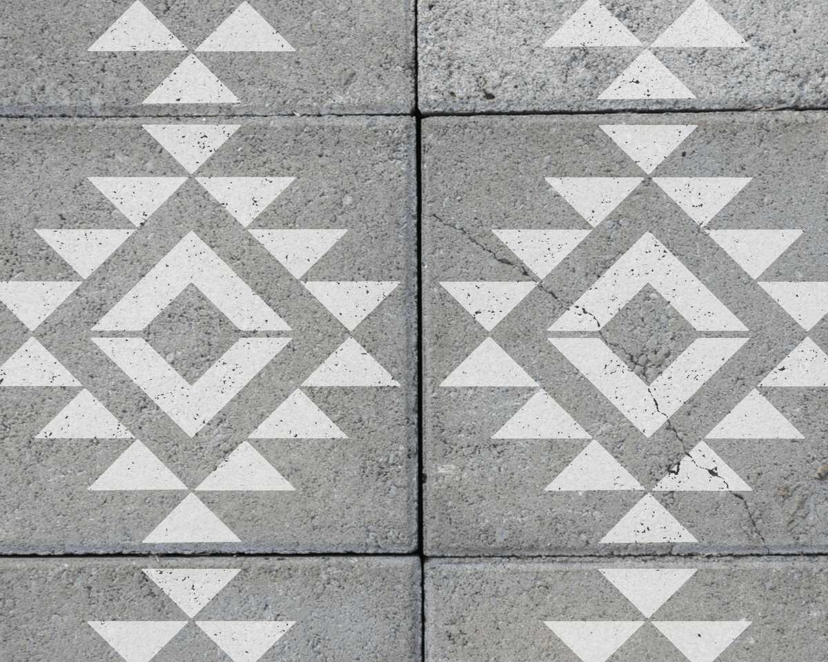 a close-up view of a patterned concrete surface with a repeating geometric design composed of white triangles and diamonds.